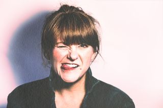 A white woman with reddish hair winks and sticks her tongue out at the viewer
