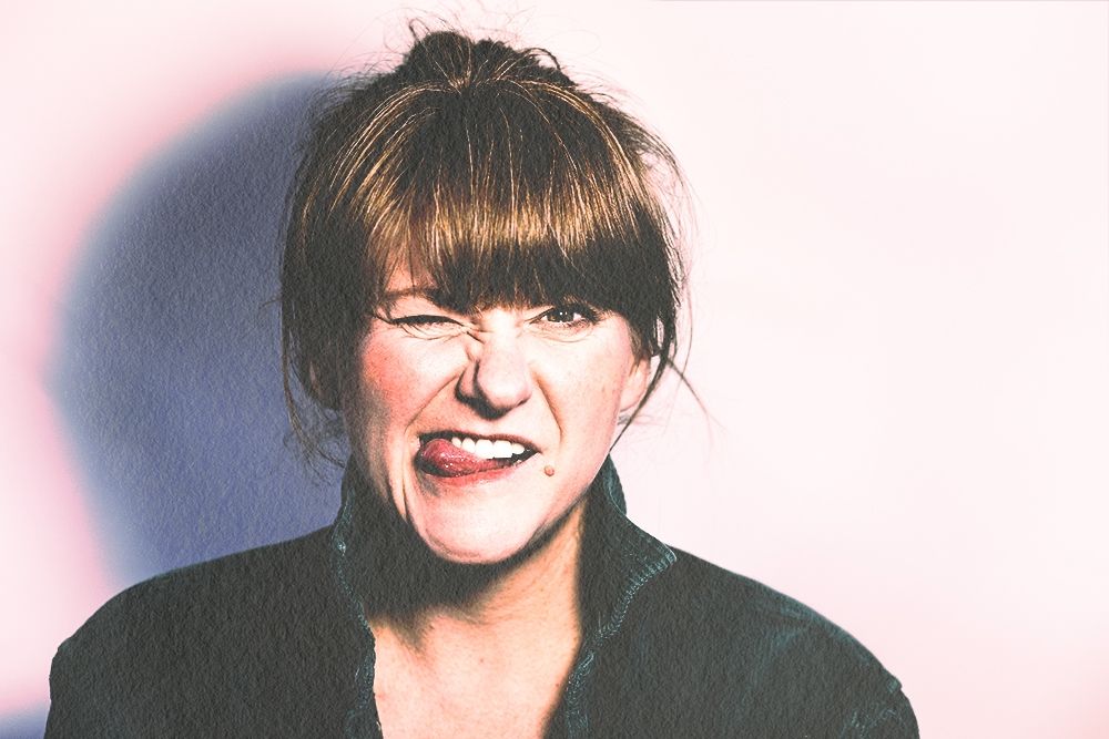A white woman with reddish hair winks and sticks her tongue out at the viewer